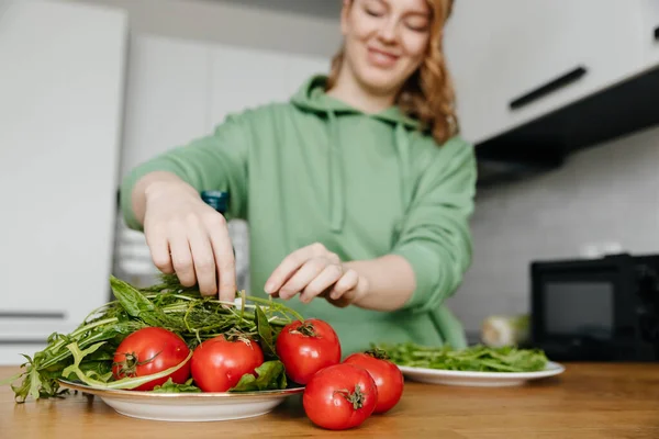 Жінка готує свіжий овочевий салат на кухні з сучасним інтер'єром. Фокус на передньому плані . — стокове фото