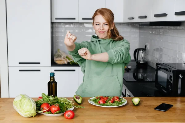 Uma jovem feliz preparando o jantar na cozinha e dançando olhando para a câmera — Fotografia de Stock