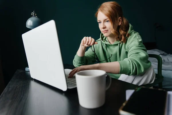 Fiatal vörös hajú nő dolgozik otthon a laptop Jogdíjmentes Stock Fotók