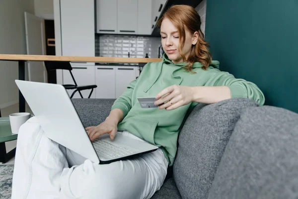 Молода руда біла жінка вдома купує онлайн за допомогою ноутбука Ліцензійні Стокові Фото