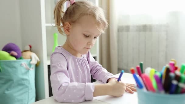 Mała dziewczynka z blond włosami rysuje kolorowymi ołówkami, śledzi jej dłoń — Wideo stockowe