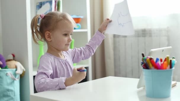 Маленька дівчинка вчиться малювати онлайн, використовуючи Інтернет і планшет . — стокове відео