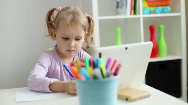 Маленькая девочка учится рисовать онлайн с помощью Интернета и планшета — стоковое видео