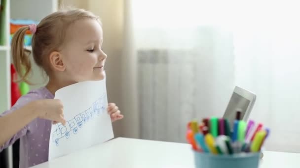 Маленькая девочка учится рисовать онлайн с помощью Интернета и планшета. — стоковое видео
