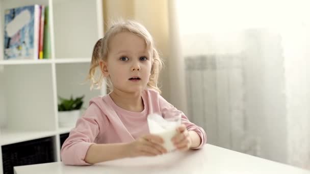 Niña con cabello rubio bebe leche o yogur — Vídeo de stock