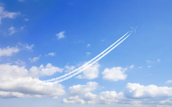 Αεροπλάνο flys σε άσπρα σύννεφα σε ένα μπλε ουρανό και αφήνει ίχνος — Φωτογραφία Αρχείου