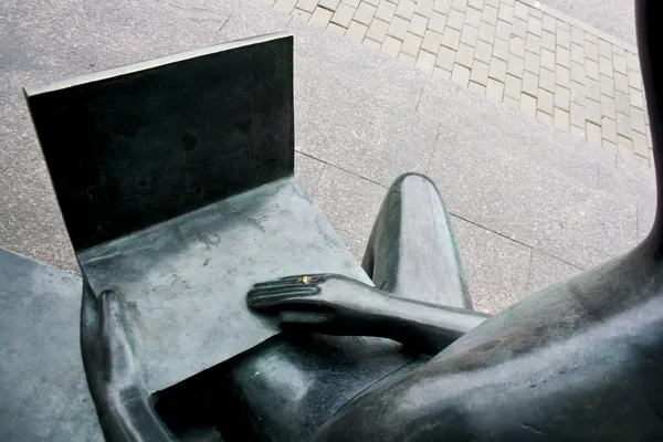 Bronzen sculptuur van een computergebruiker zitten met een notebook op overlappingen — Stockfoto