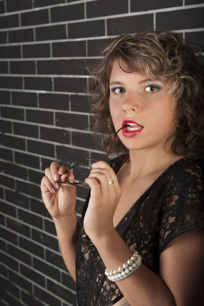 Lockiges Mädchen mit Brille im schwarzen Kleid — Stockfoto