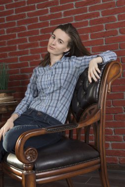 Genç bir kadın sandalyede oturuyor.