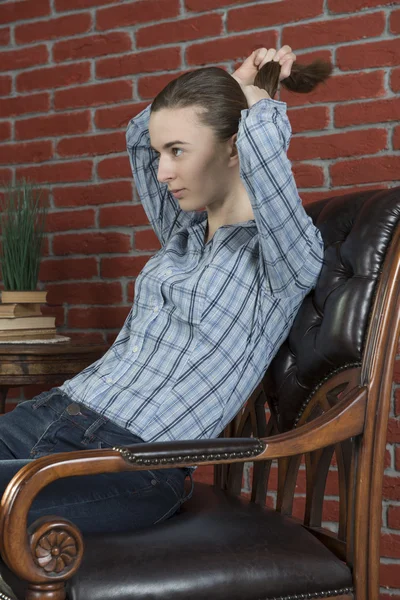 Jenta i stolen retter ut håret sitt. – stockfoto