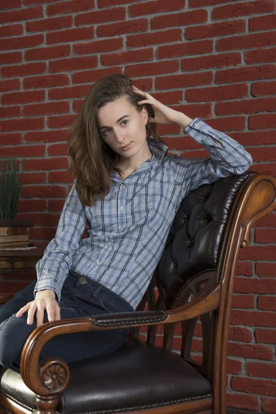 Young woman sits in a chair — Stock Photo, Image