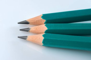 Beyaz arka planda, yakın plan makro fotoğrafçılığında üç basit tahta kalem keskinleştirilmiş.