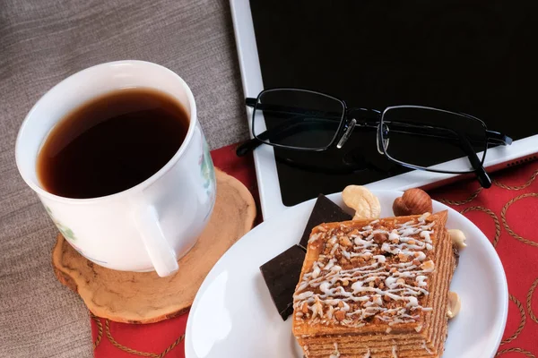 平板电脑旁边放着一杯浓郁的红茶 桌上放着松饼坚果蛋糕 — 图库照片