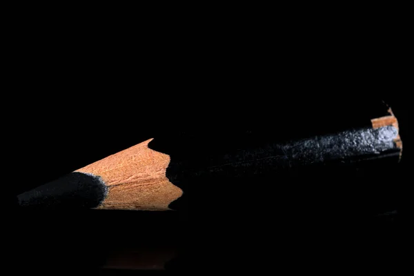 黒の鏡のような背景には 古い小さな使用された鋭利な黒い木製のスレートの鉛筆がありますクローズアップ — ストック写真