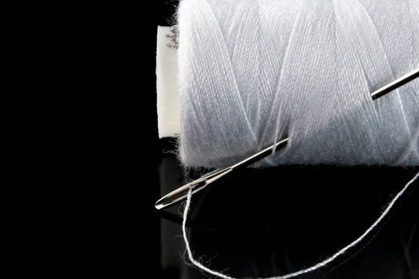 黒い背景に白い糸と針が挿入されたスプールクローズアップマクロ写真 — ストック写真