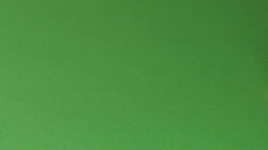 Keskinleştirilmiş küçük bir kırmızı kalem yeşil kağıt üzerinde duruyor ve kamera yakın çekim video klibine göre hareket ediyor