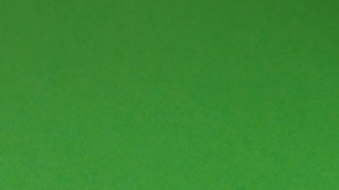 Yeşil kağıt ataçta üç küçük kırmızı, mavi ve siyah kalem görünüyor.