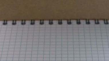 Keskinleştirilmiş küçük bir kırmızı tahta kalem görünür ve açık kareli bir defter, video klip, yakın plan üzerinde durur.
