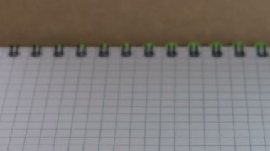 Keskinleştirilmiş küçük kırmızı, mavi ve yeşil tahta kalemler görünür ve açık kareli bir defter üzerinde durur, video klip, yakın plan