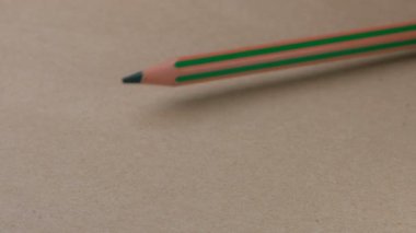 İki yeşil kalemin savaşı, ufaklığın kahverengi bir karton yüzey üzerinde kazandığı zaferle biter. Video klipsi, yakın plan.