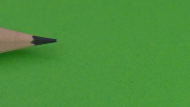 左側にシンプルな木製の鉛筆が表示され 緑色の背景に消しゴム ビデオクリップ クローズアップで右側の鉛筆でブロックされます — ストック動画