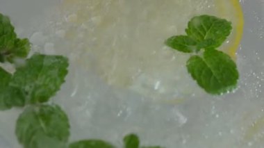 Karbonatlı içeceği nane ve bir dilim limonu cam bardakta yakın çekimde yavaş çekimde tazeliyorum.