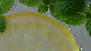 Karbonatlı içeceği nane ve bir dilim limonu cam bardakta yakın çekimde yavaş çekimde tazeliyorum.