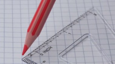 Kırmızı bir kalem açık kareli bir defter üzerinde cetvel ile düz bir çizgi çizer, yakın çekim, yavaş çekim, video klip