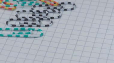 Çok renkli ataçlar ve işaretlenmiş bir dizüstü bilgisayarda bir düğme hareketi, yakın çekim, yavaş çekim, video klipsi