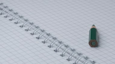 Küçük keskinleştirilmiş kırmızı ve yeşil kalemler açık işaretli bir defterde görünür ve ayağa kalkar, yakın çekim, yavaş çekim, video klip