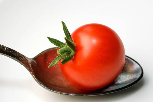 白い鏡の背景に小さじ1杯に小さな赤い熟したトマトのクローズアップ — ストック写真