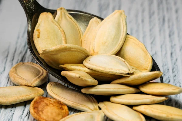 Ahşap bir masada, bir çay kaşığında kabak çekirdeği kavrulmuş.