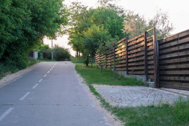 Yazın kırsal alanda, asfalt yol boyunca modern kır evleri ve çitler var.