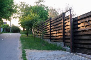 Yazın kırsal alanda, asfalt yol boyunca modern kır evleri ve çitler var.