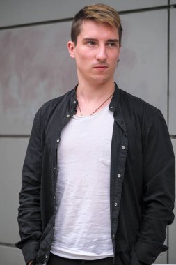 Portrait of a young handsome guy in a black shirt close-up autumn street photography