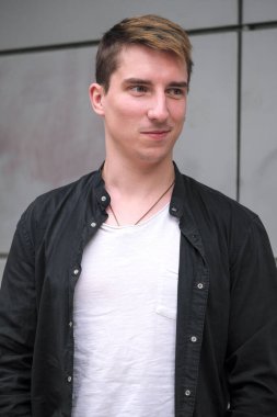 Portrait of a young handsome guy in a black shirt close-up autumn street photography