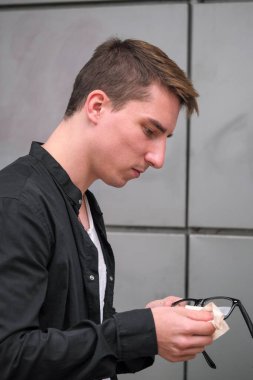 Portrait of a young handsome guy in a black shirt with glasses close-up autumn street photography
