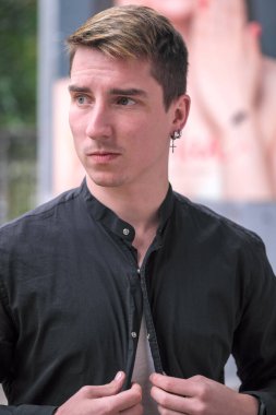 Portrait of a young handsome guy in a black shirt close-up autumn street photography