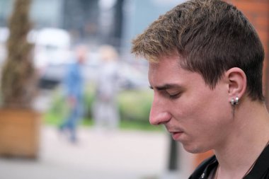 Portrait of a young handsome guy in a black shirt next to a brick wall autumn street photography