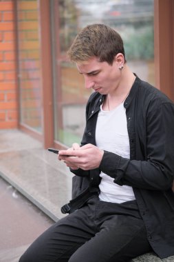 Portrait of a young handsome guy in a black shirt next to a shop window autumn street photography