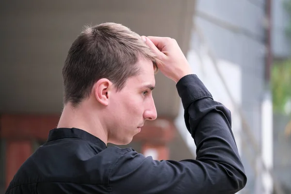 Portrait of a young handsome guy in a black shirt close-up autumn street photography