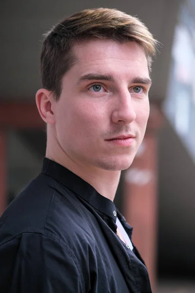 Portrait of a young handsome guy in a black shirt close-up autumn street photography