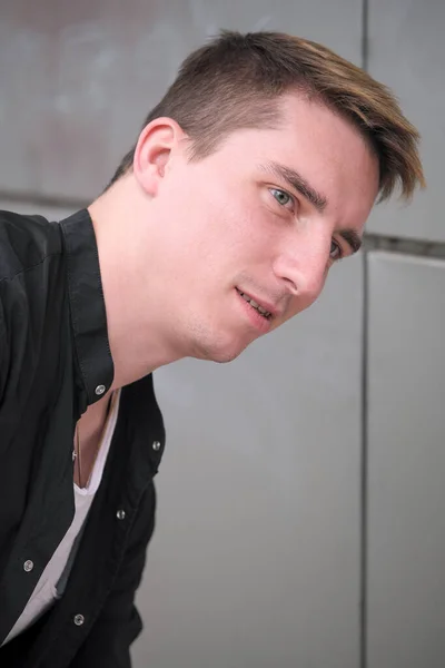 Portrait of a young handsome guy in a black shirt close-up autumn street photography