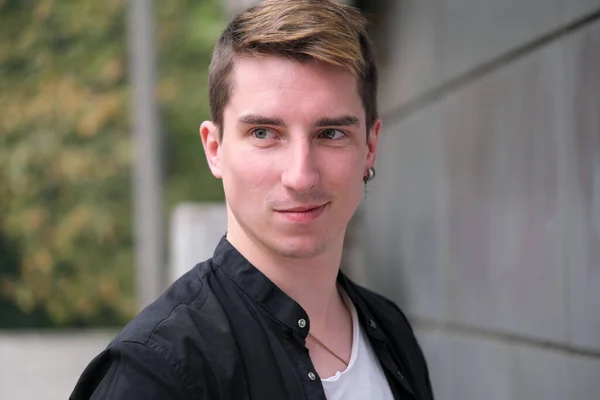 Portrait of a young handsome guy in a black shirt close-up autumn street photography