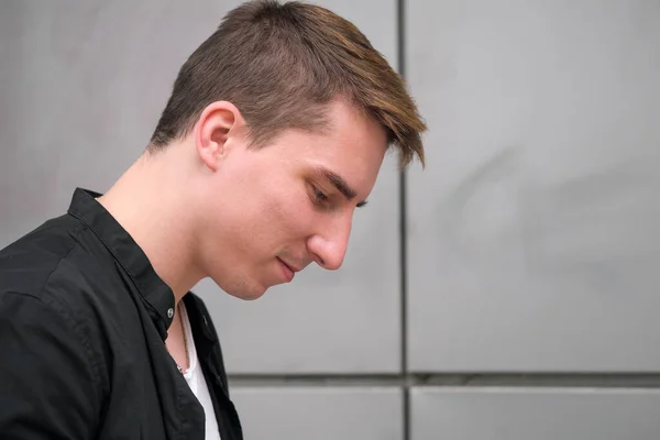 Portrait of a young handsome guy in a black shirt close-up autumn street photography