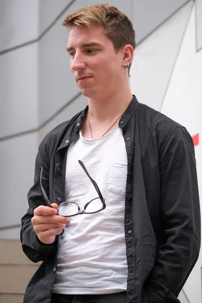 Portrait of a young handsome guy in a black shirt close-up autumn street photography