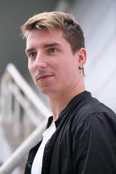 Portrait of a young handsome guy in a black shirt close-up autumn street photography