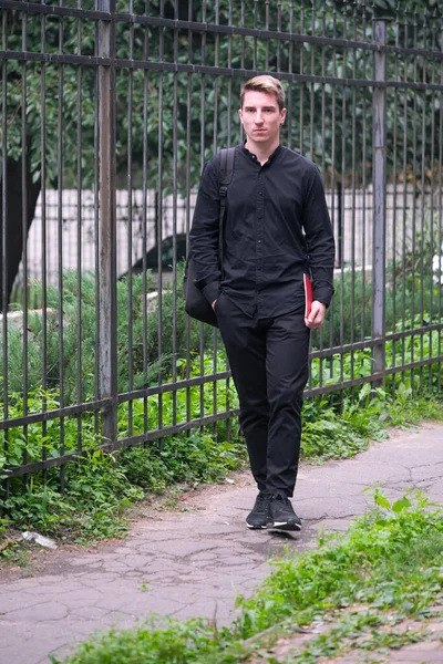 Portrait of a young handsome guy in a black shirt close-up autumn street photography