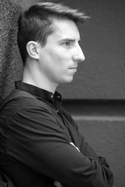 Black and white portrait of a young handsome guy in a black shirt autumn street photography