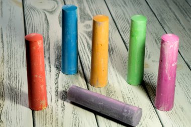 Alacakaranlık ışığı kırtasiyesinde beyaz ahşap bir masaya çizim yapmak için renkli boya kalemleri. Eğitim arka planı.